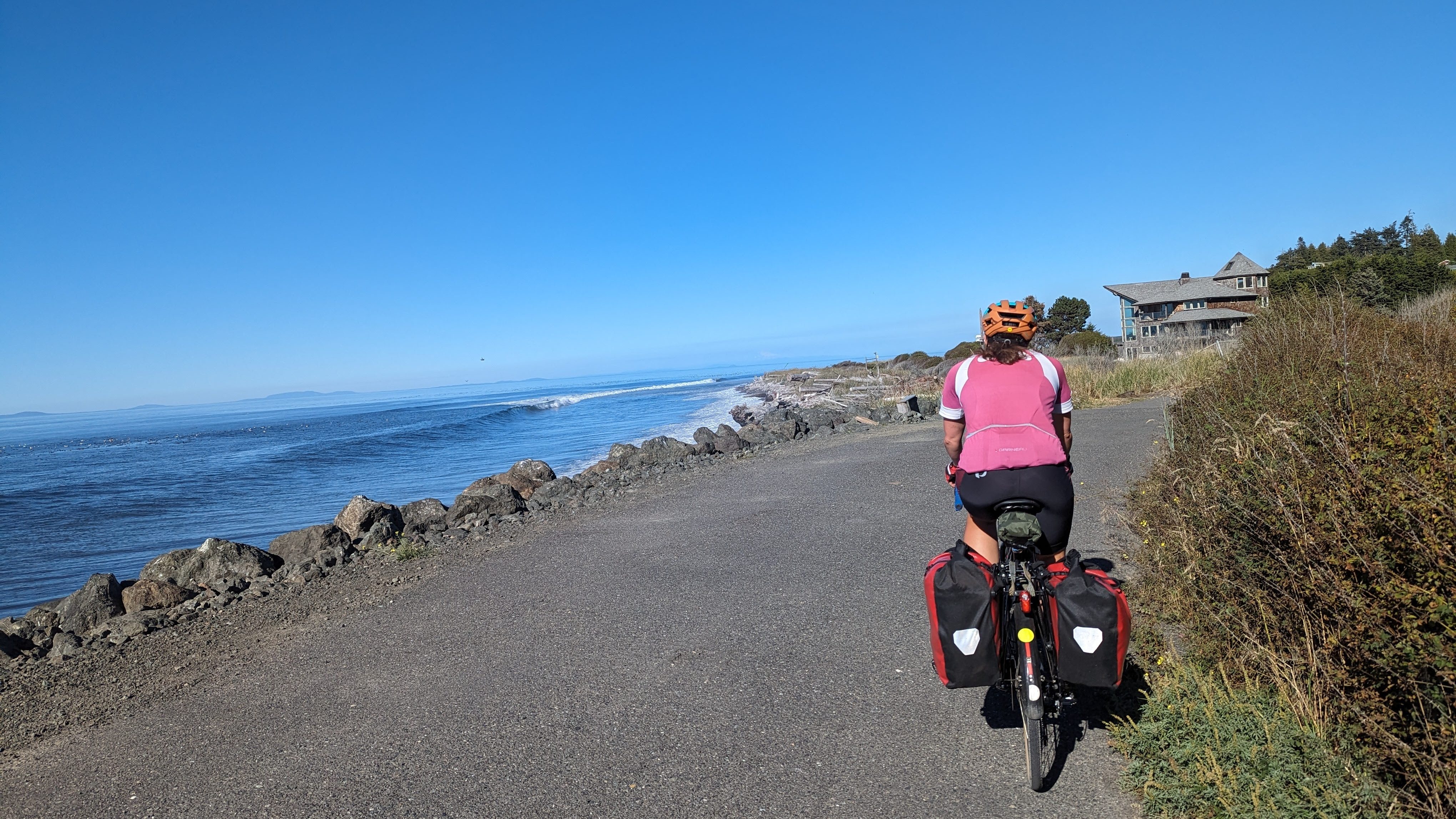 A woman biking on a trail next to the ocean